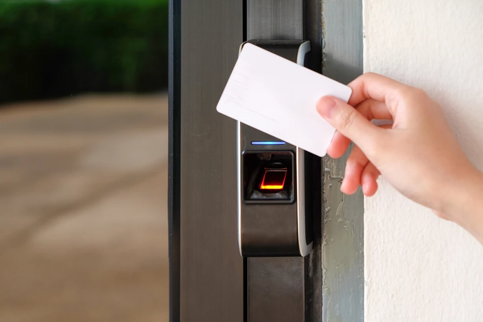 Scène intérieure montrant une main tenant une carte d'accès blanche devant un lecteur de contrôle d'accès électronique