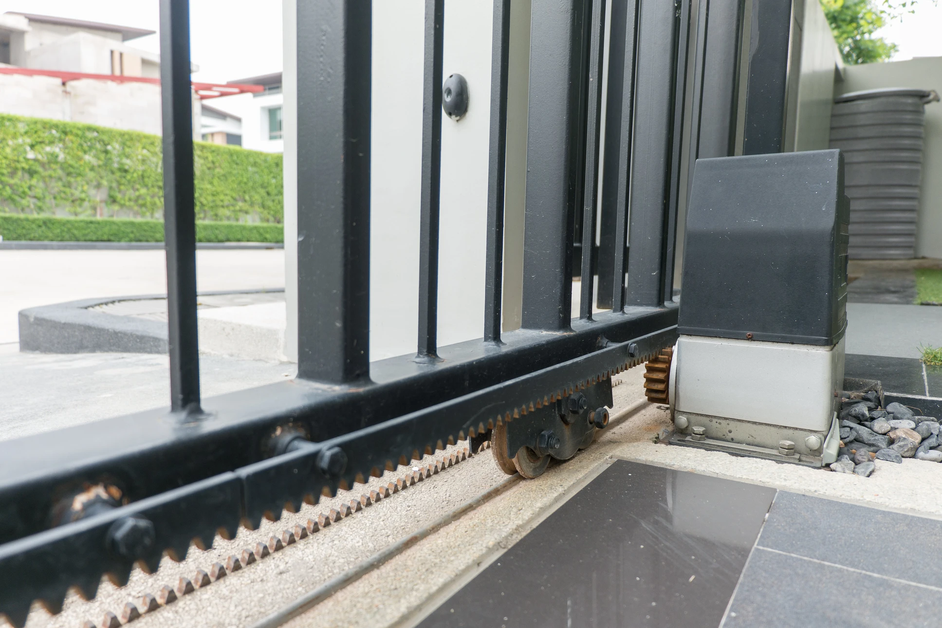 Extérieur commercial avec rideau métallique fermé gris installé dans encadrement béton blanc, sol carrelage beige avec joints apparents