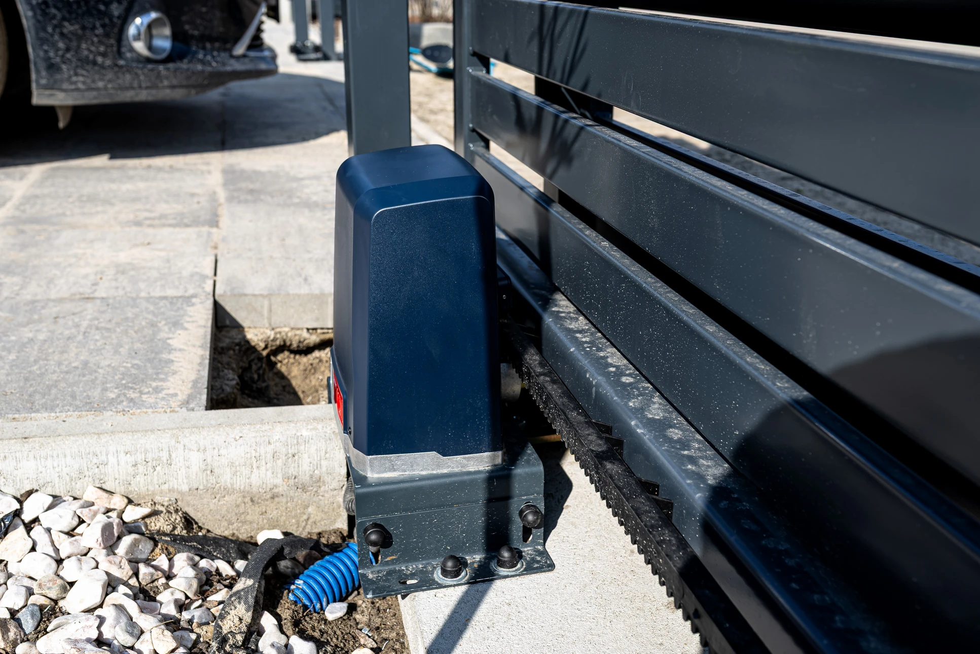 Technicien en combinaison bleue avec gants de protection noirs effectuant une intervention de maintenance sur équipement électrique industriel