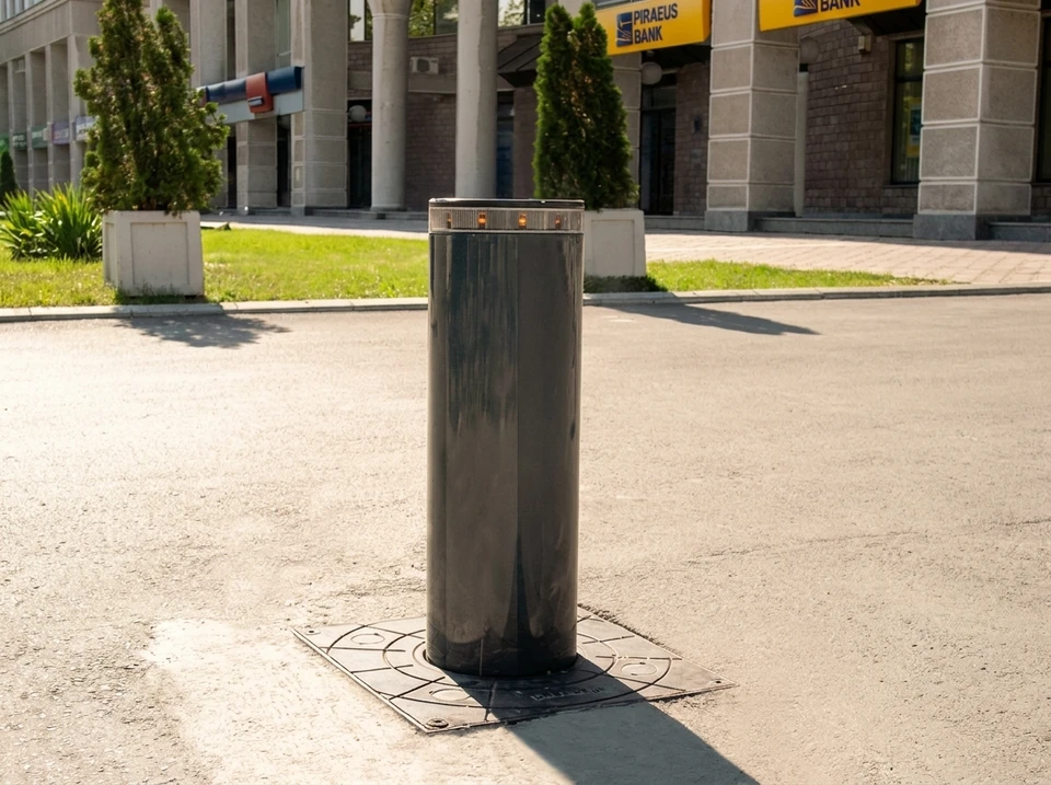 Entrée résidentielle avec portail automatique en fer forgé orné de volutes décoratives, flanqué de piliers en béton blanc équipés d'interphones et luminaires